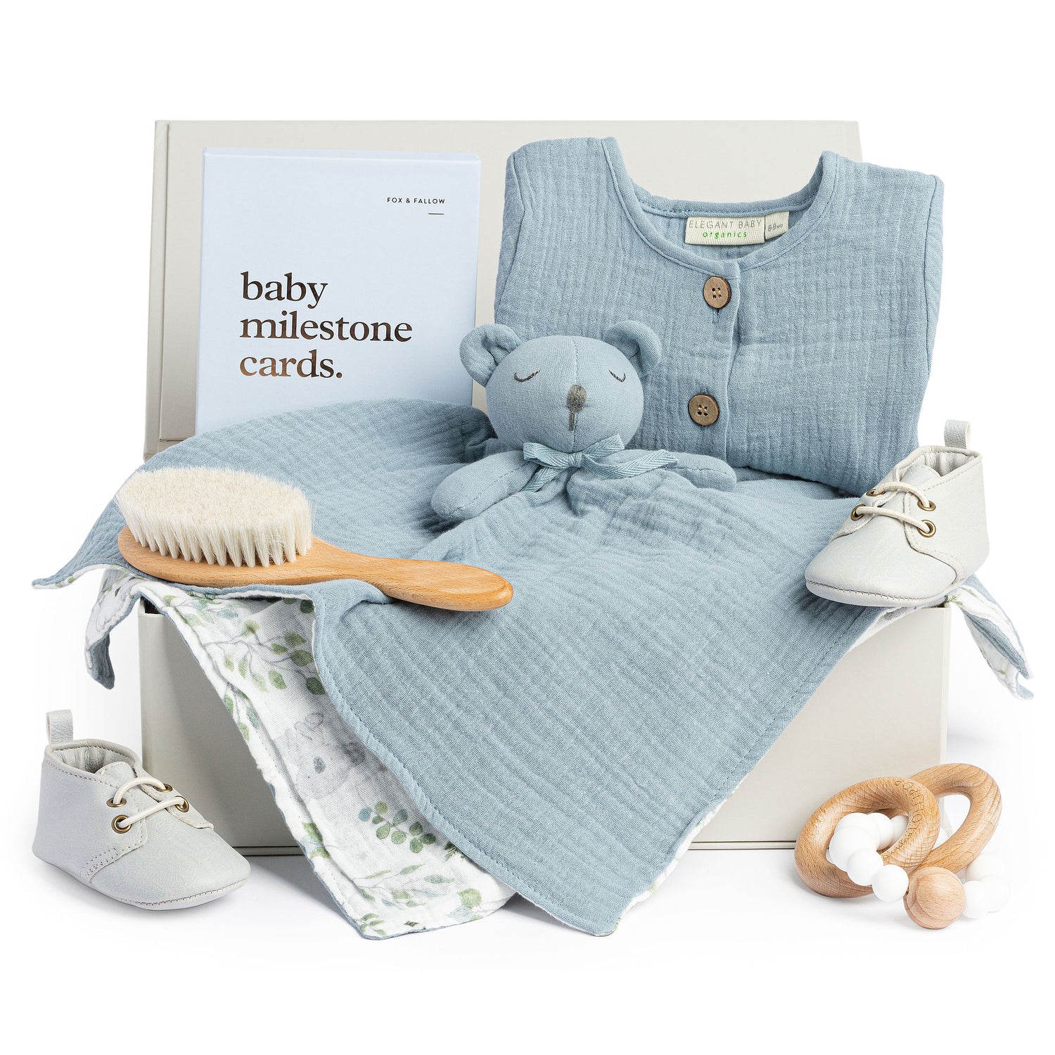 Baby boy gift box with blue romper, blue security blanket, white baby moccasins and blue milestone cards.