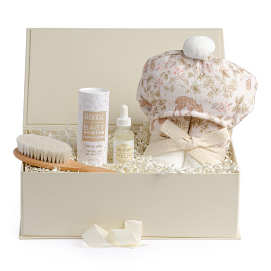 Baby bath gift set with a light pink fawn bath wrap, baby oil, organic baby powder and a wooden hair brush.