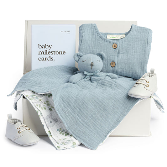 Anna & Amy grey gift box with baby  blue muslin jumpsuit, light grey shoes, baby milestone cards and teddy security blanket.